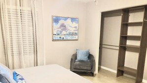 Ein Schlafzimmer mit einem Bett, einem Sessel, einem Kleiderschrank und einem Bild an der Wand.