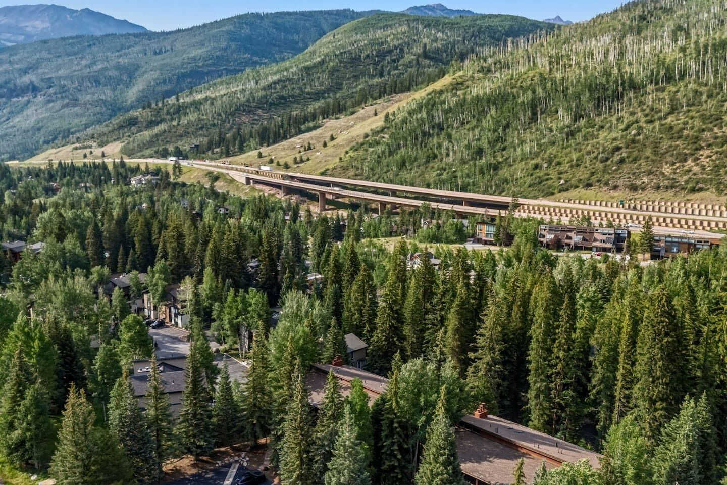 Une région montagneuse comprenant un pont autoroutier, une forêt dense et des immeubles d’habitation.