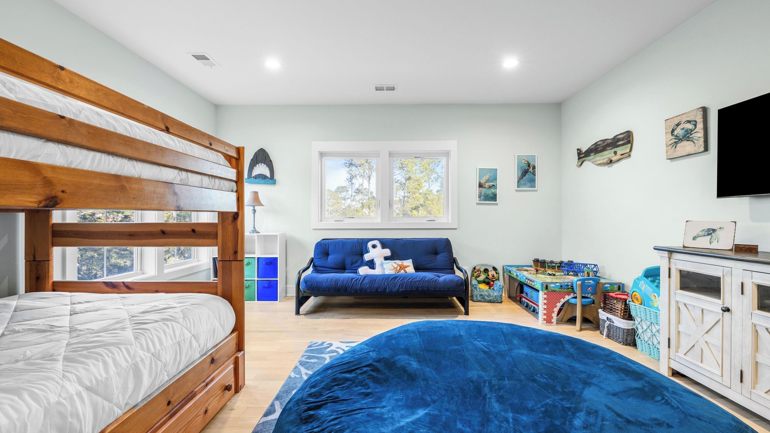 Une chambre avec un lit superposé, un canapé, un espace de jeux et un téléviseur.
