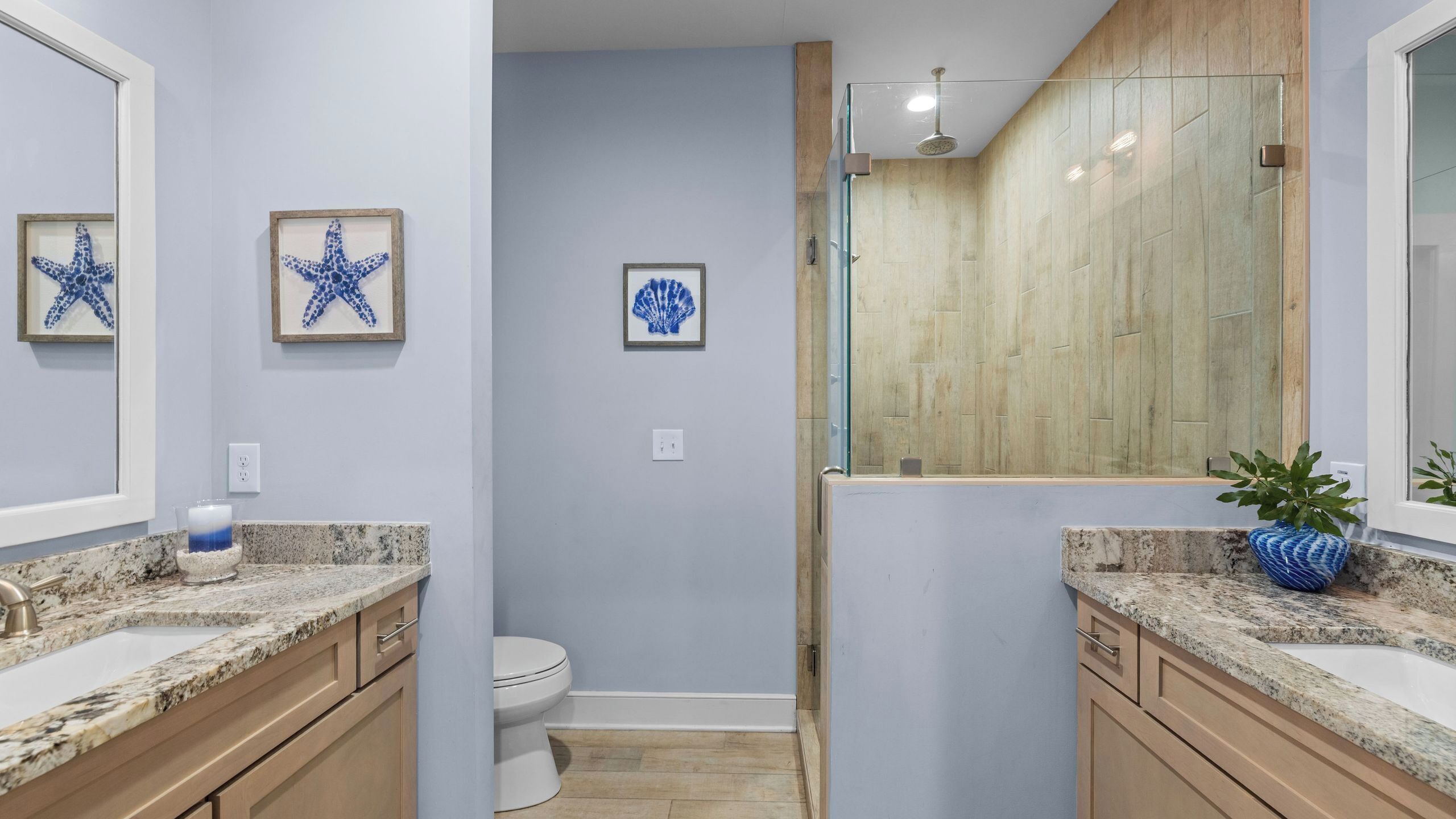 Une salle de bain équipée d’une douche, de toilettes et de deux lavabos avec des plans de travail en marbre.