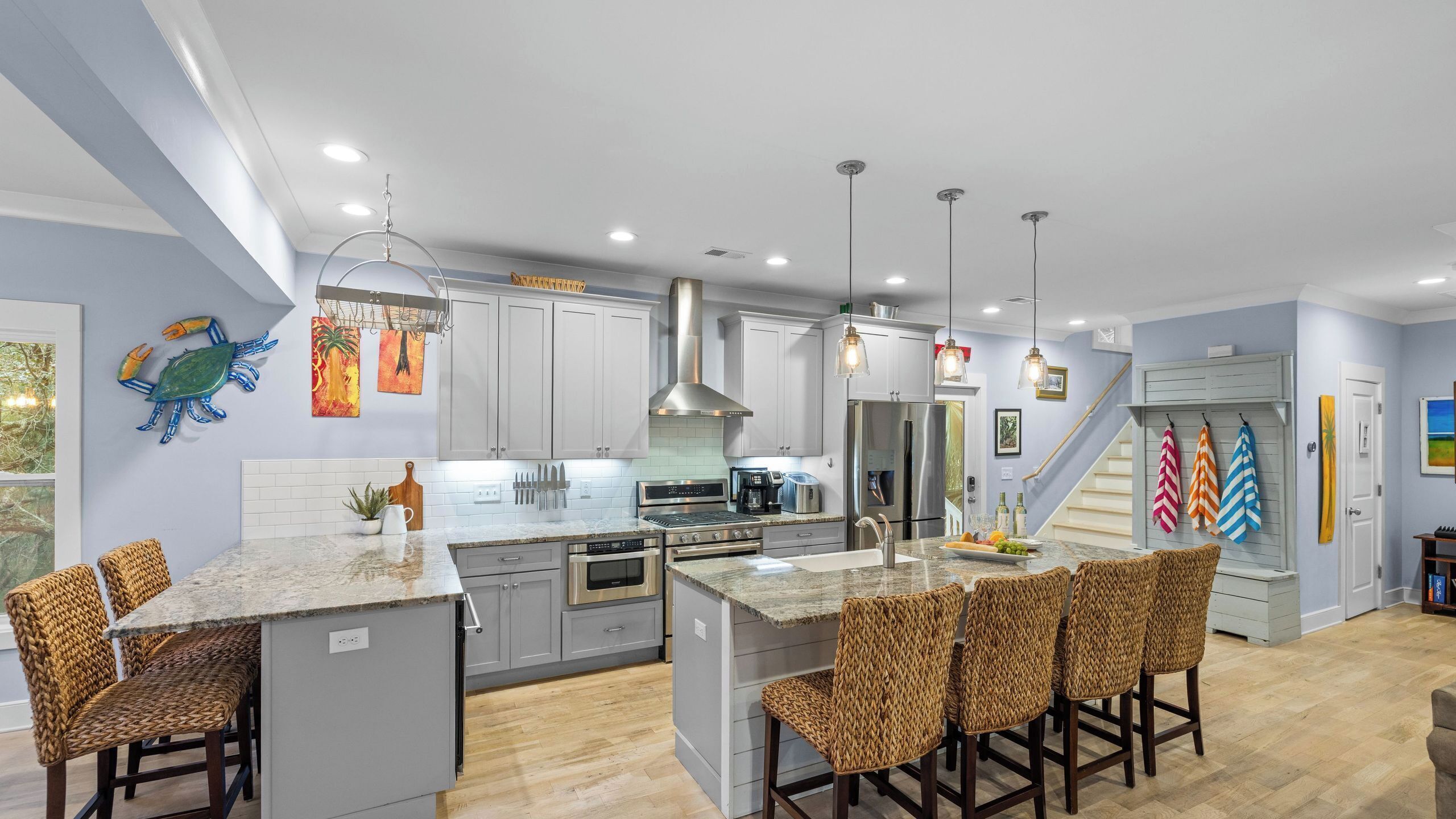 A modern kitchen with grey cabinets, stainless steel appliances, and a central island with bar stools.
