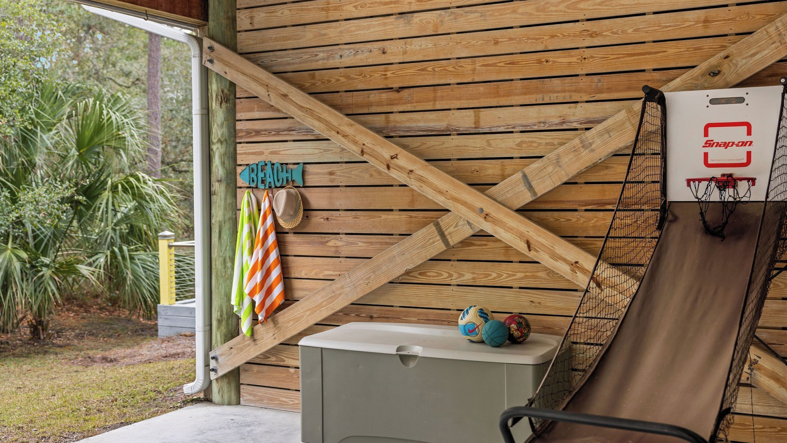 A wooden structure with a basketball hoop, a towel rack, and a sign that reads 'BEACH'.
