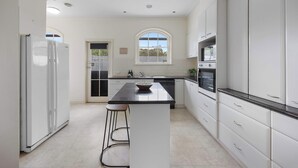 Une cuisine moderne avec des meubles blancs, un îlot central et une grande fenêtre.