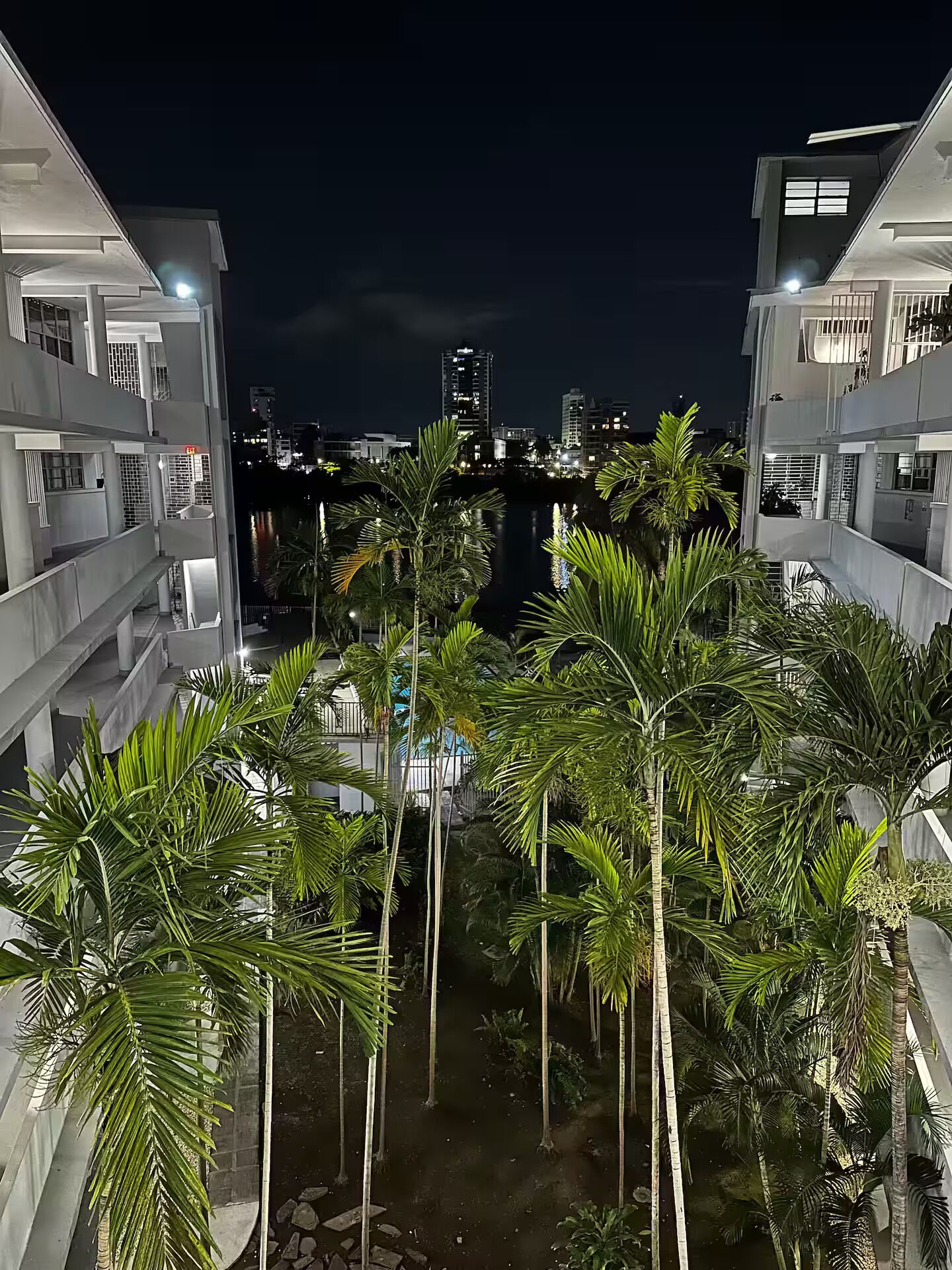 A nighttime view of a modern building with multiple balconies overlooking a waterway.