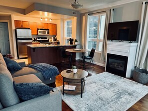 A modern living room with a gray sofa, a coffee table, and a fireplace. - Chic Downtown Suite w/ AC & Parking | Near Rogers (Edmonton)