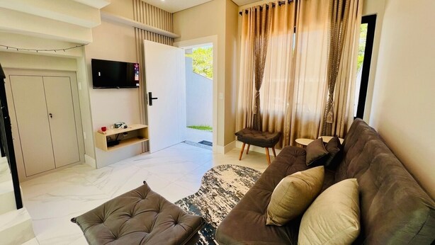 Un salon moderne avec un canapé marron, un pouf assorti et un téléviseur à écran plat fixé au mur.