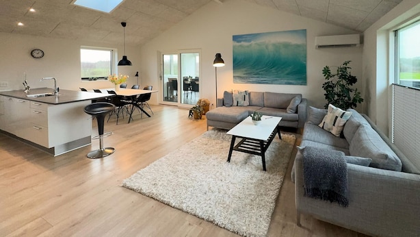 Um espaço moderno para relaxar, com cozinha, área de refeições e um sofá grande.