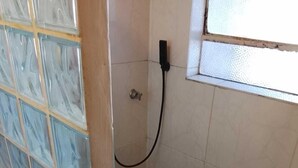 A small, tiled shower area with a glass door, a showerhead, and a window. - apartamento de temporada  (Uruguaiana)