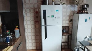 A compact kitchen with a refrigerator, a microwave, and a sink. - apartamento de temporada  (Uruguaiana)