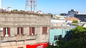 A building with a red awning, a tower in the background, and surrounding greenery. - apartamento de temporada  (Uruguaiana)