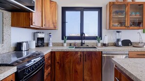 Eine moderne Küche mit Holzausstattung, einem eingebauten Herd, einer Kaffeemaschine und einem Fenster mit Blick.