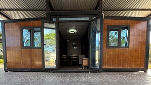 A modern, open-plan structure with a tiled floor, large windows, and a ceiling with a corrugated metal design.
