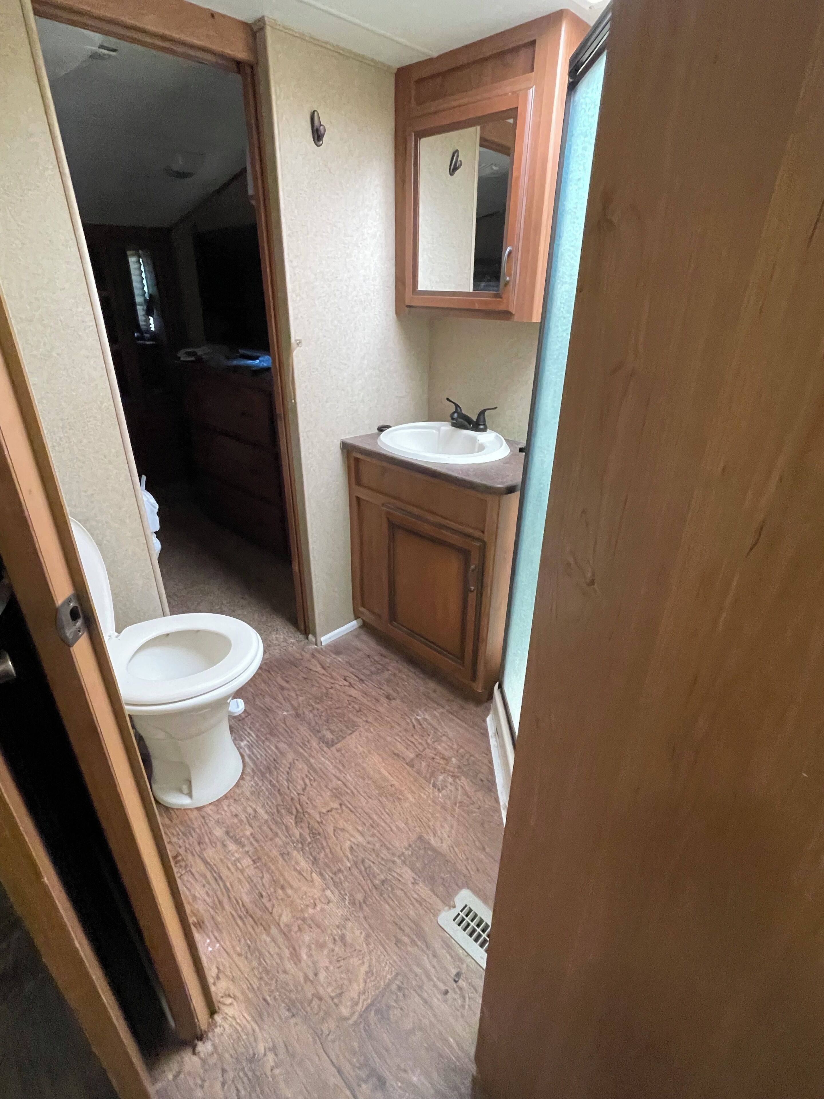 Une petite salle de bain comprenant des toilettes, un lavabo et un meuble en bois.
