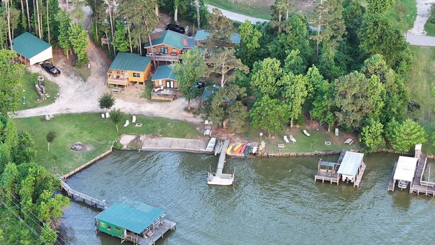 A lakeside property with a dock, a boat, and a small boat house. - RV #1 - delightful 1-bdrm, 3 slide out, covered deck, at Lake Livingston Tx  (Onalaska)