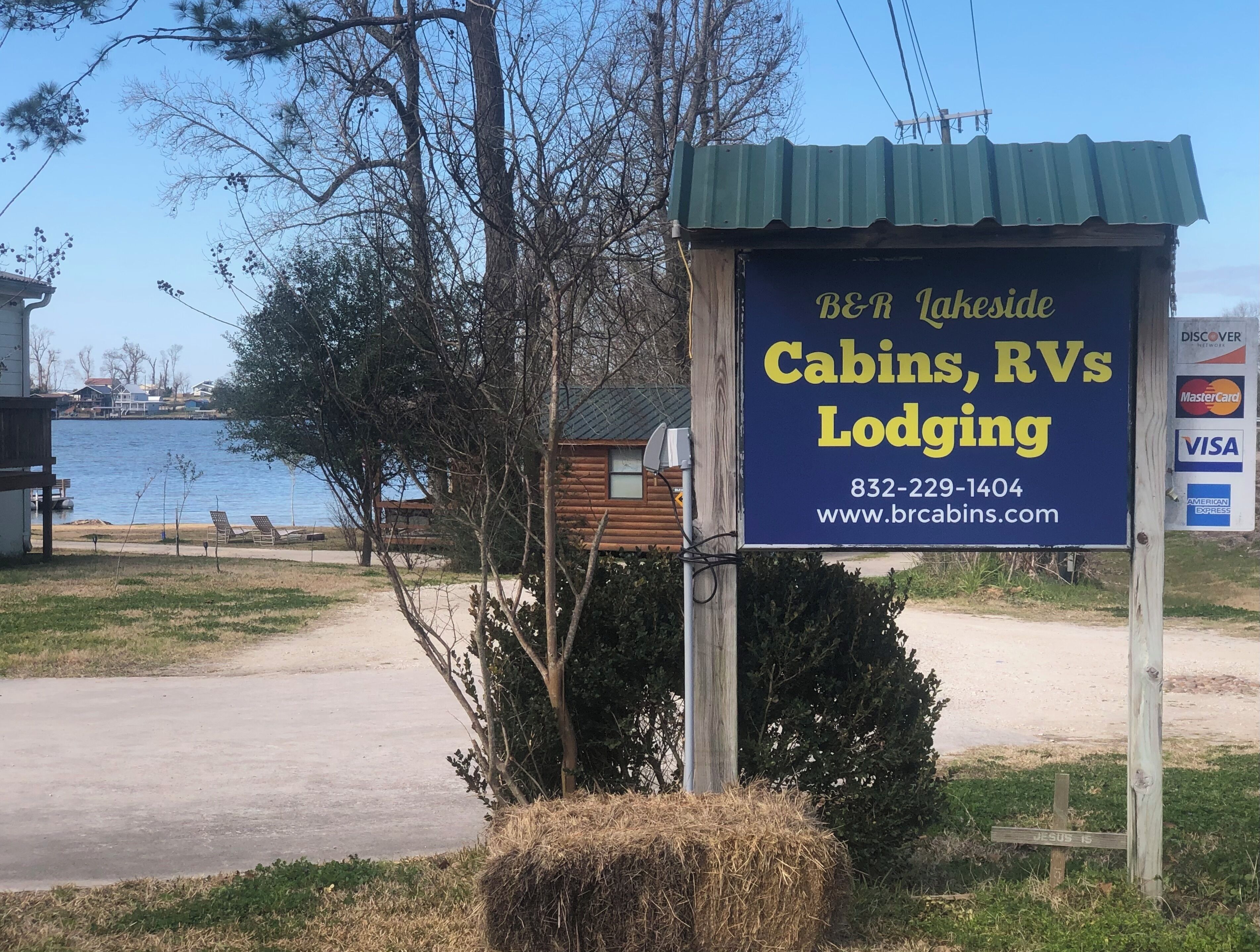B&R Lakeside Cabins -majoituspaikan kyltti, jossa on tietoja matkailuautoille tarkoitetuista paikoista sekä yhteystiedot ja verkkosivuston osoite.