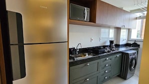 A modern kitchen with a stainless steel refrigerator, a microwave, a sink, and a built-in washing machine. - New apartment one block from the beach with ocean view and garage. (Vila Velha)