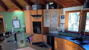 Cuina amb illa central, armaris de fusta i finestra que deixa entrar llum natural.