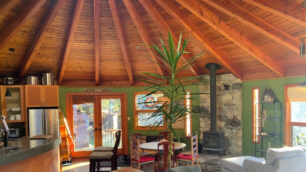 Un interior acollidor amb sostre de fusta, una llar de pedra, zona de dinar i saló amb sofà.