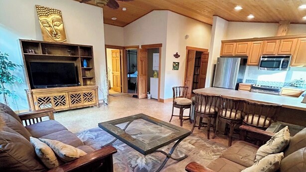 A spacious living room with a large TV, wooden furniture, and a ceiling fan. - Charming Private Suburban Cottage, Serene & Cozy (Mount Vernon)