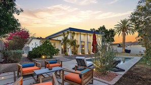 Ein modernes Haus mit Terrasse, Gartenmöbeln und einem Swimmingpool.