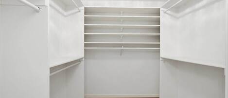 A walk-in closet with white walls and wooden flooring.
