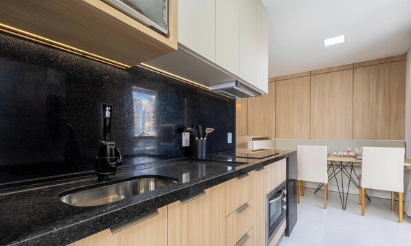 A modern kitchen with black granite countertops, stainless steel appliances, and wooden cabinetry. - Apt w/ Balcony & BBQ 350m From the Sea Eim0301 (Picarras)