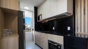 Egy modern konyha, melyben fa szekrények, fekete munkalap és beépített sütő található.