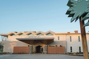 The exterior of the Crystal Court Hotel with a modern architectural design, featuring a prominent entrance, a brick facade, and a clear sky. - Caravan Court Hotel (Arlington)