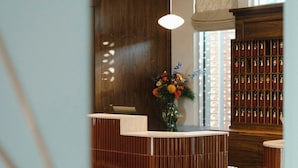 A reception desk with a vase of flowers, a wooden cabinet with a patterned design, and a stone floor.