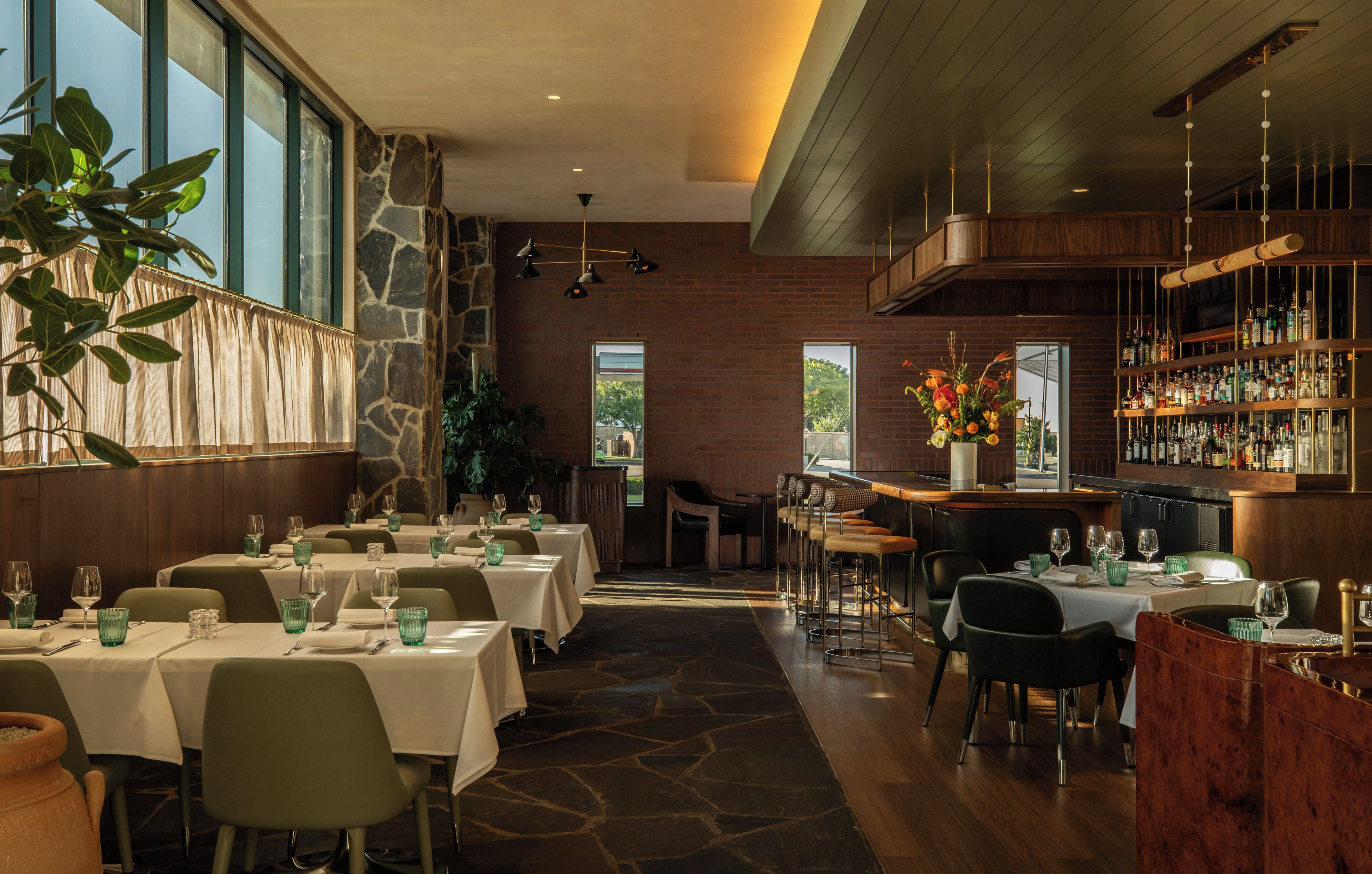 Un restaurante con varias mesas, una zona de bar y vistas al exterior.