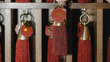 A hand selecting a keychain with a tassel from a wooden shelf.