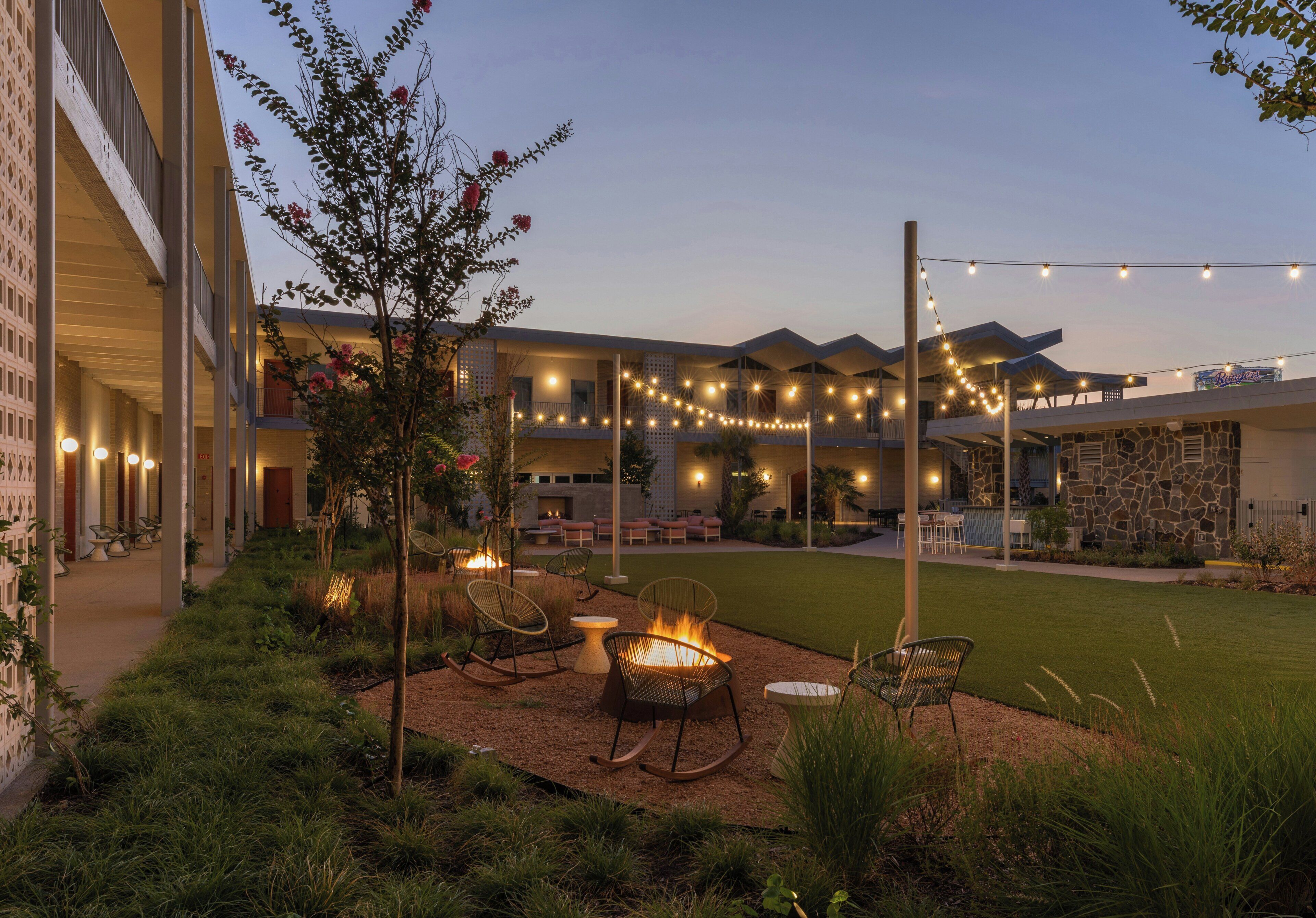 Un patio con mobiliario exterior, luces colgantes y un brasero.