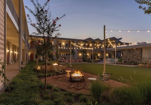 A courtyard with outdoor seating, string lights, and a fire pit. - Caravan Court, Valencia Collection (Arlington)