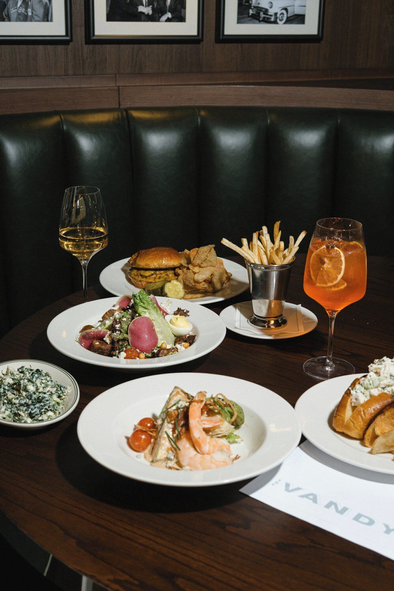 Una mesa de comedor con varios platos, bebidas y una carta.