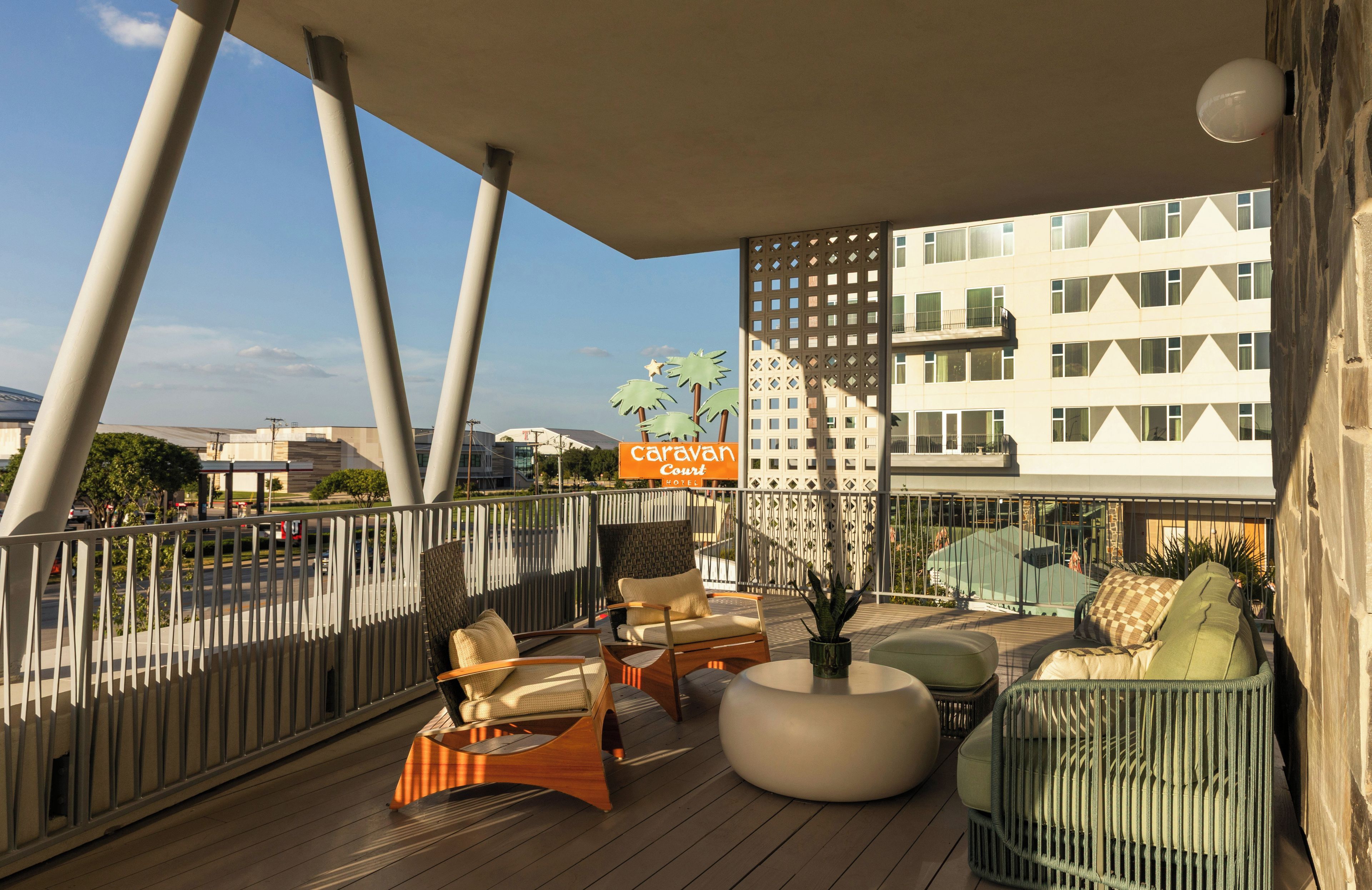 A balcony with outdoor seating, a potted plant, and a hotel sign.
