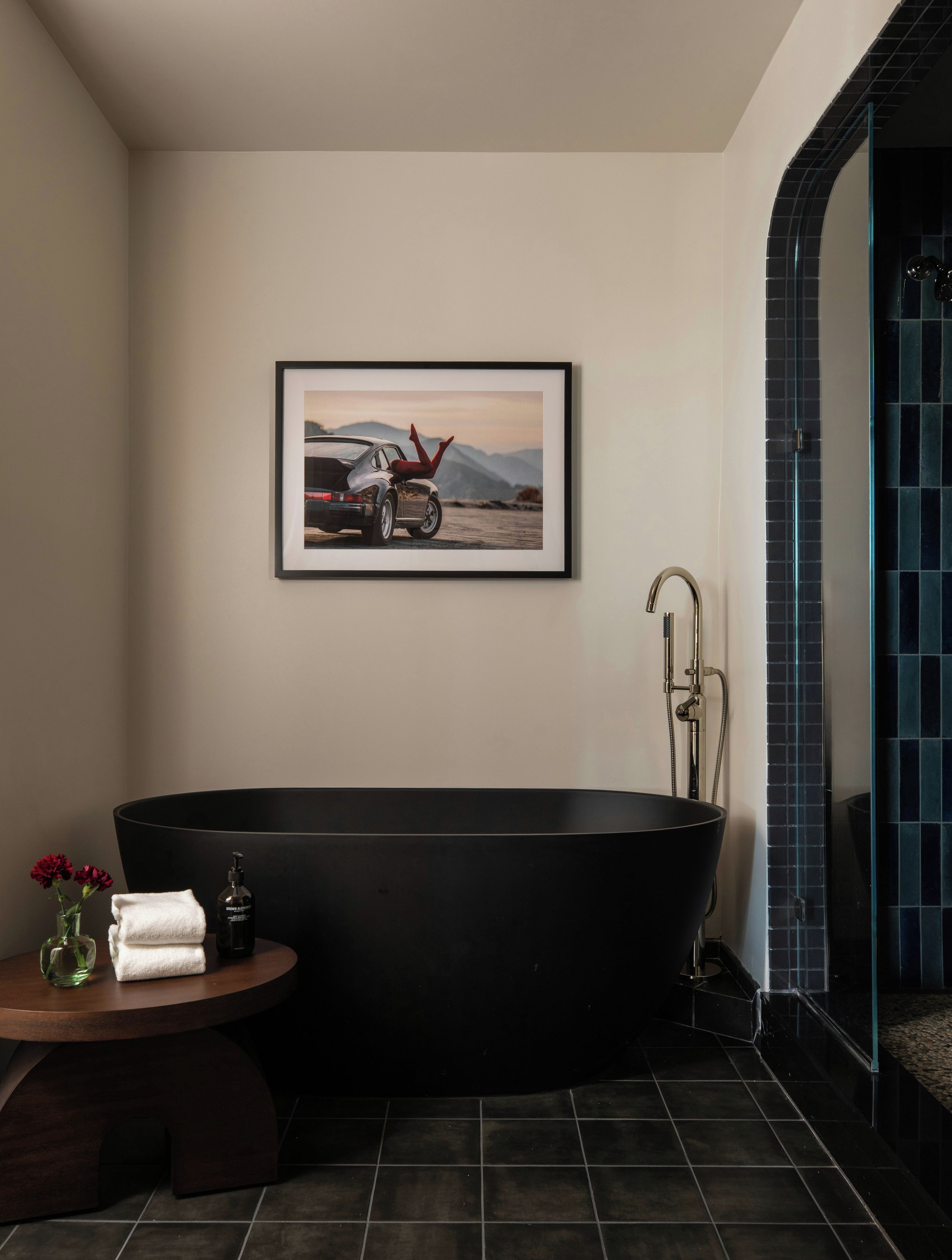 Ein modernes Badezimmer mit einer freistehenden Badewanne, einem gerahmten Bild an der Wand und einem kleinen Tisch mit Toilettenartikeln.