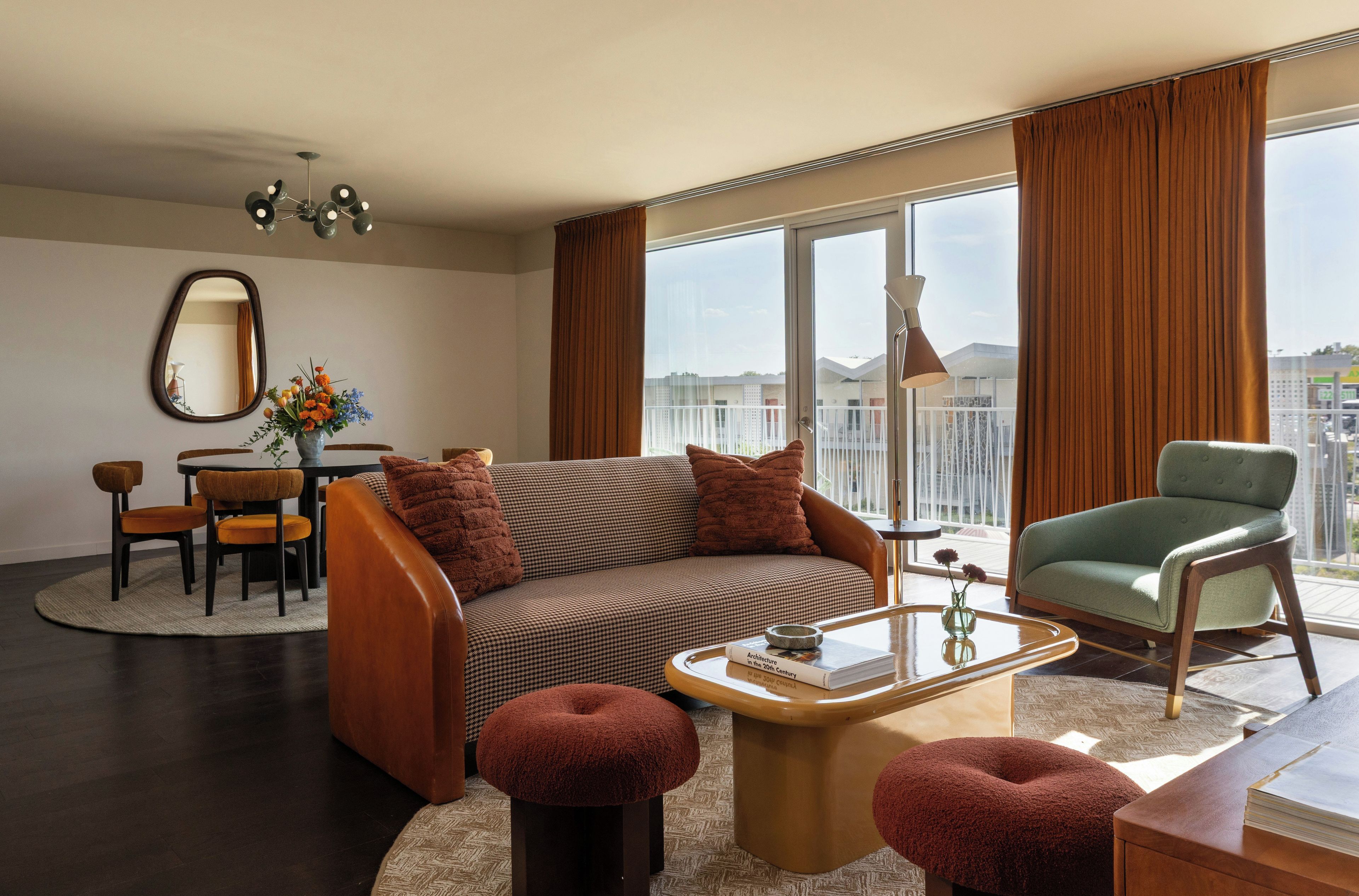 A modern living room with a sofa, ottomans, a coffee table, and a dining area with chairs and a table.
