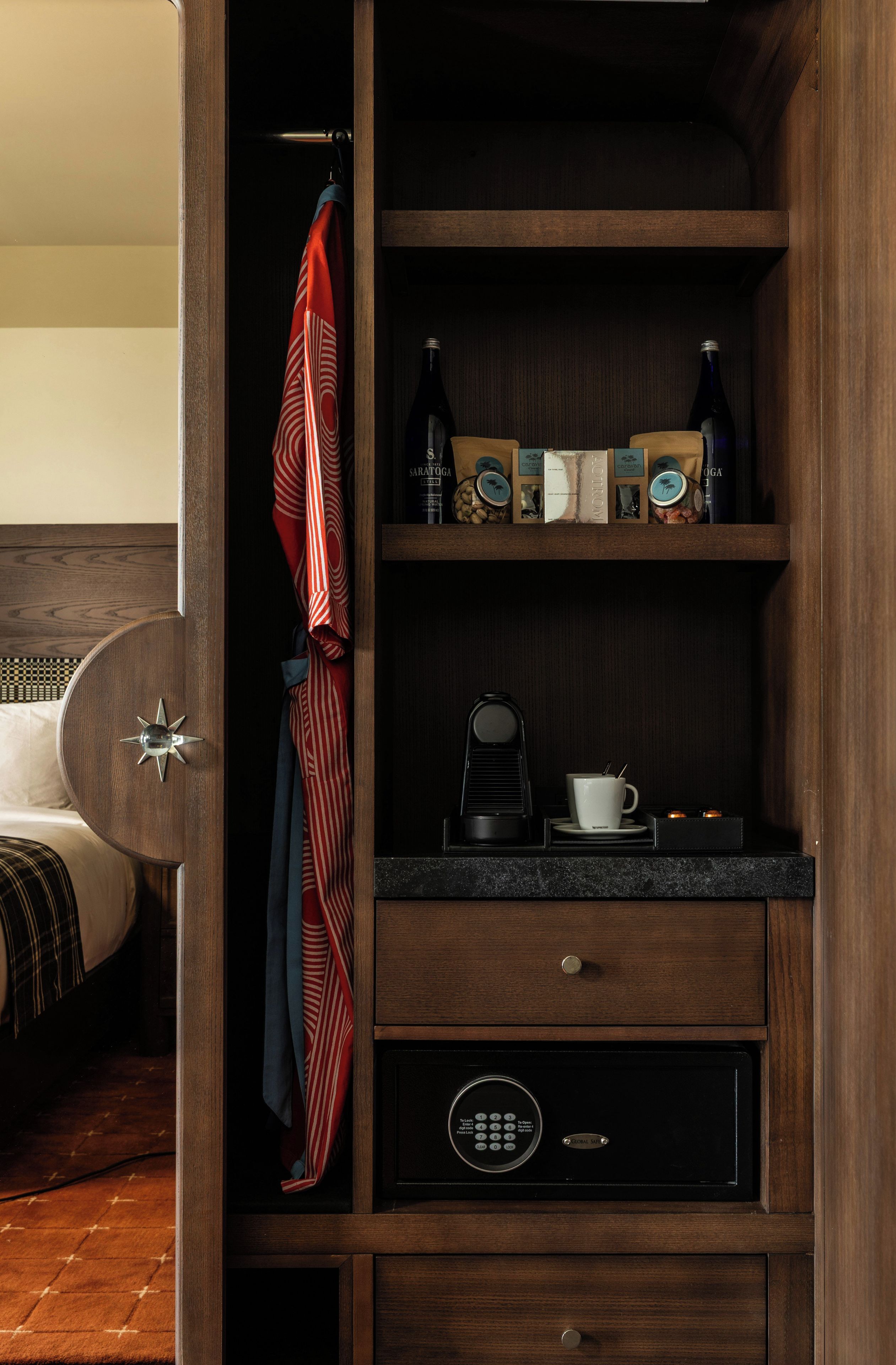 Un mueble de madera con una cafetera, una taza y un libro en una estantería.
