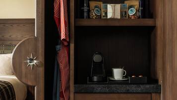 Un mueble de madera con una cafetera, una taza y un libro en una estantería.