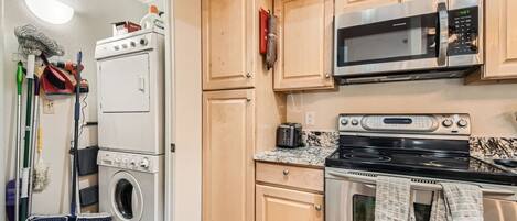 Una cucina compatta con forno a microonde, forno e lavatrice.