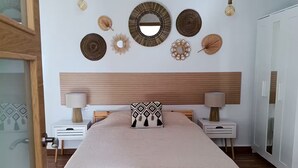 Ein Schlafzimmer mit einem Holzbett, zwei Nachttischen, einem großen Spiegel und Wanddekoration.