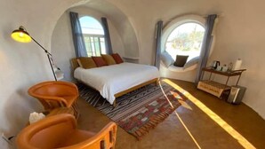 Ein Schlafzimmer mit einem Bett, einem kleinen Tisch, einem Stuhl und einem Fenster.