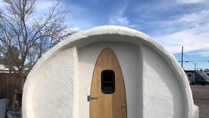 Eine kuppelförmige Struktur mit einer Holztür und einem kleinen Fenster.