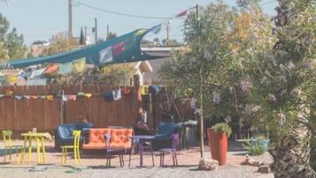 Ein Terrassenbereich im Freien mit Holzzaun, bunten Wimpeln und Gartenmöbeln.