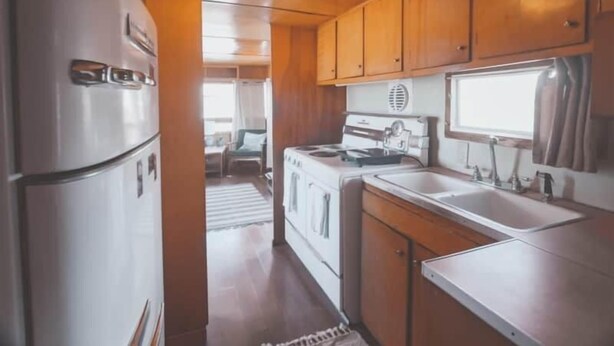 Una cocina compacta con gabinetes de madera, un refrigerador, una estufa y un lavaplatos.