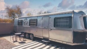 Un camping-car d’époque est garé sur une surface goudronnée, à proximité d’un passage pour piétons.