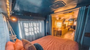 Un lit confortable avec des coussins à motifs, un fauteuil suspendu et une fenêtre avec des rideaux.