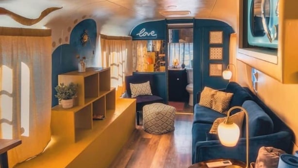 Un intérieur chaleureux avec un canapé bleu, une petite table et une étagère ornée d’objets décoratifs.