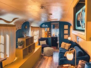 Un intérieur chaleureux avec un canapé bleu, une petite table et une étagère ornée d’objets décoratifs.