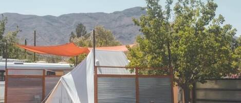 A campsite with a white tent, a red canopy, and a metal fence.